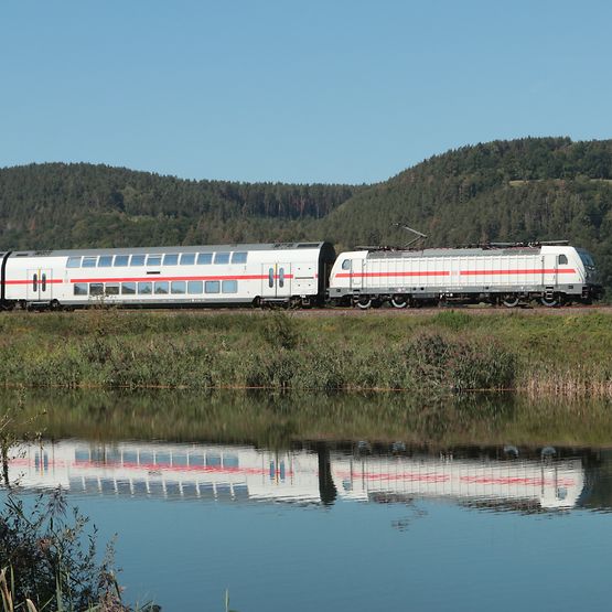 Unterwegs im Tal der Saale bei Etzelbach in Thüringen: Ein IC2 mit E-Lok der Baureihe 147 spiegelt sich in der Saale.
