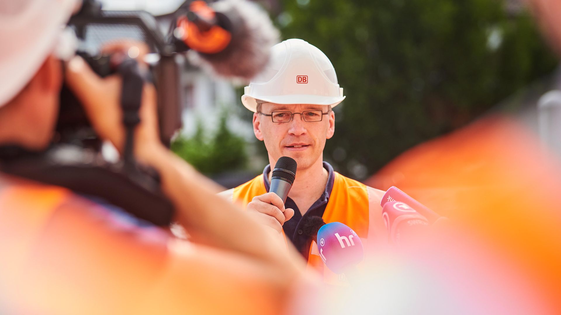 Projektleiter Julian Fassing mit Mikrofon auf der Riedbahn-Baustelle