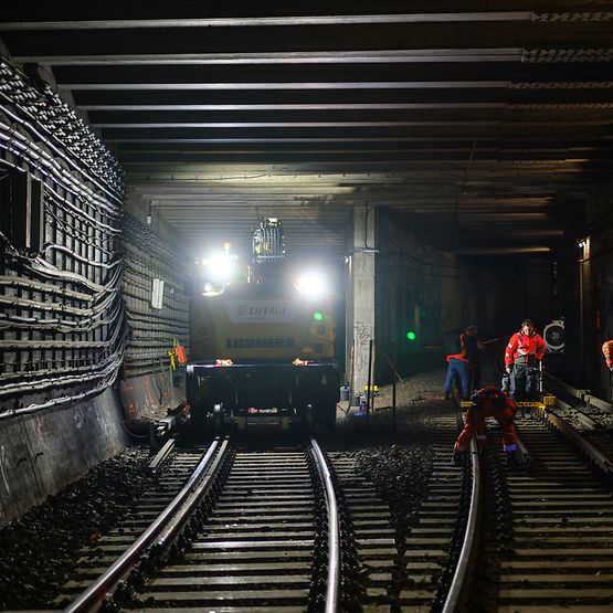 Zweiwegebagger und Bauarbeiter auf den Gleisen im S-Bahn-Nordsüdtunnel in Berlin