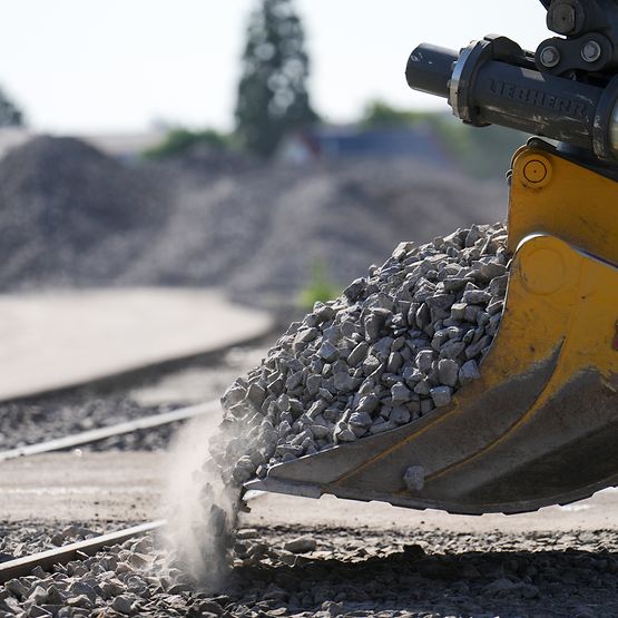 Bagger verteilt Schotter auf dem Gleisbett
