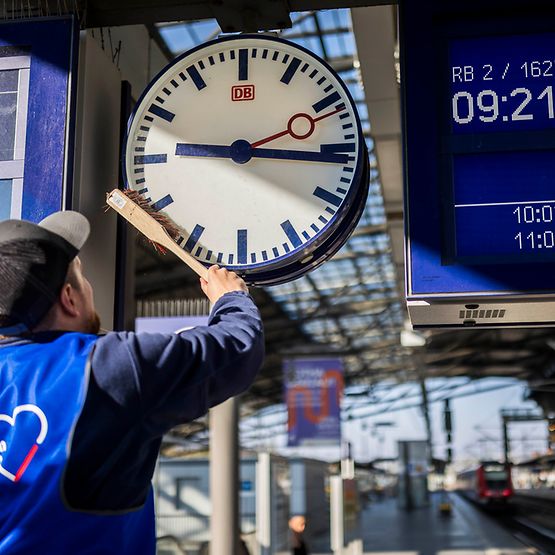 Mitarbeiter reinigt Bahnhofsuhr