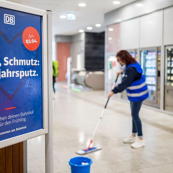 Mitarbeiterin putzt Fußboden in Bahnhof