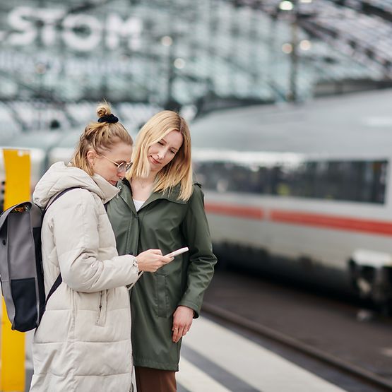 Zwei Reisende informieren sich in der App DB Navigator über ihre Verbindung.