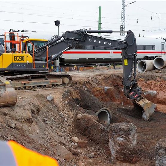Baustelle mit Bagger und ICE im Hintergrund