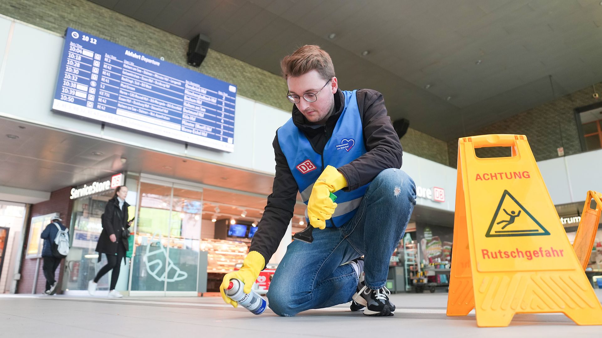 Ein Mitarbeiter entfernt Dreck vom Boden des Bahnhofshalle