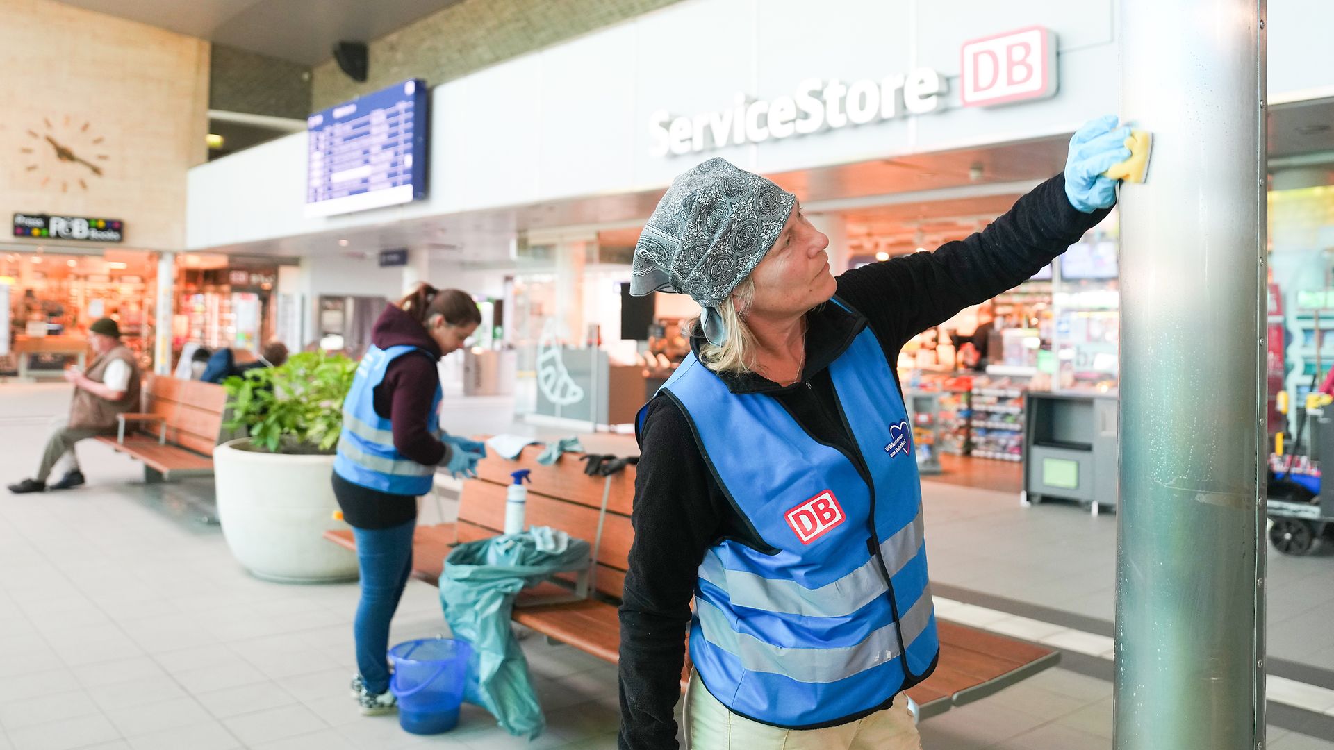 Helferin reinigt Säule in der Bahnhofshalle