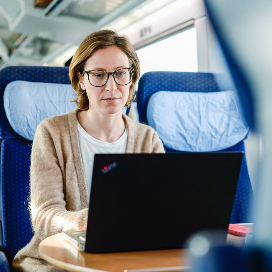 Frau im Zug arbeitet am Laptop.