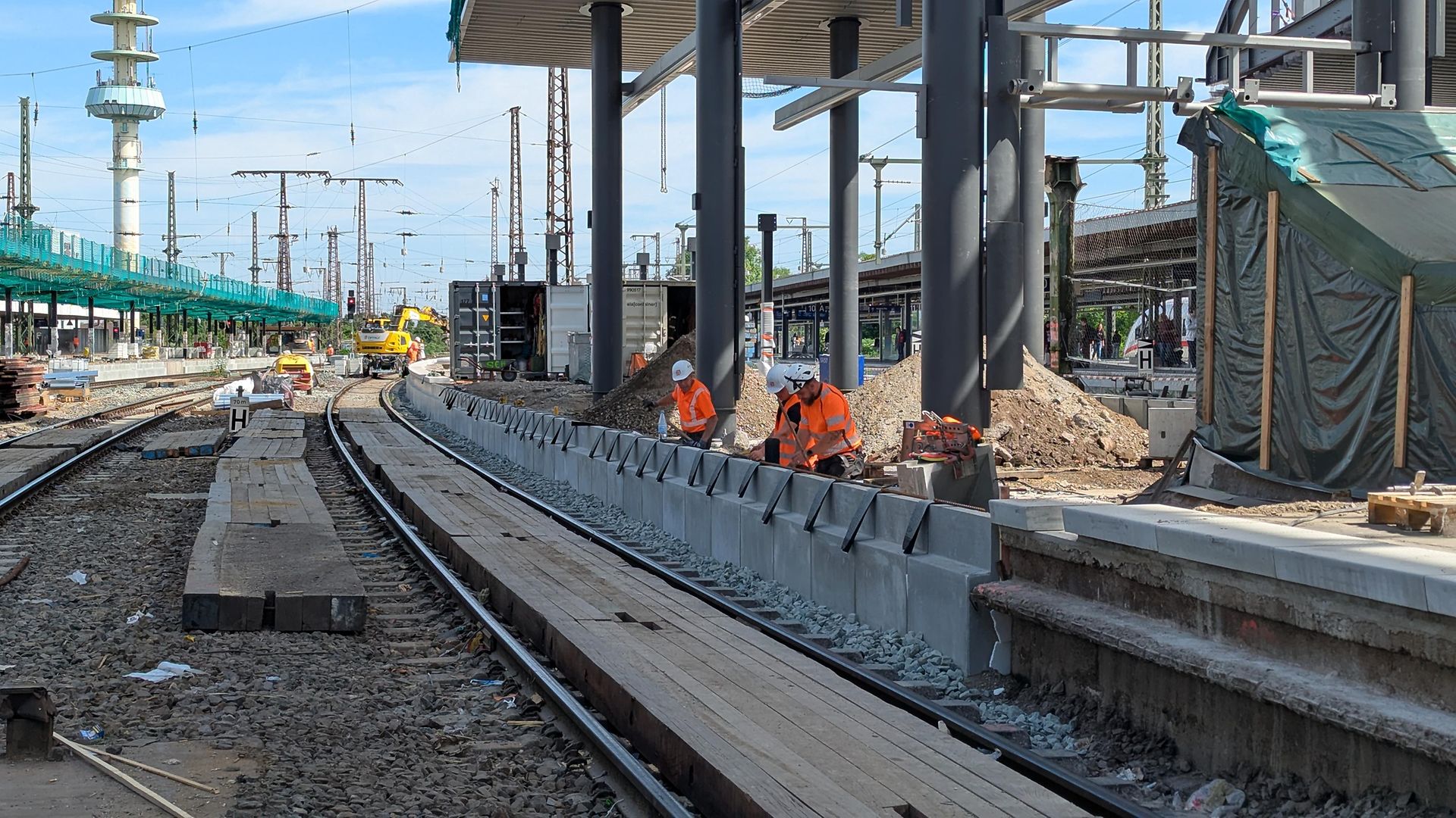 Mehrere Baufachleute arbeiten an der Bahnsteigkante