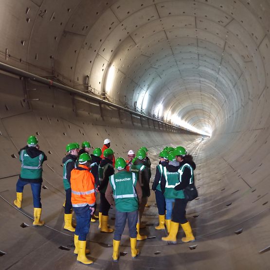 Eine Gruppe mit Bauhelmen steht in einem Tunnel. 
