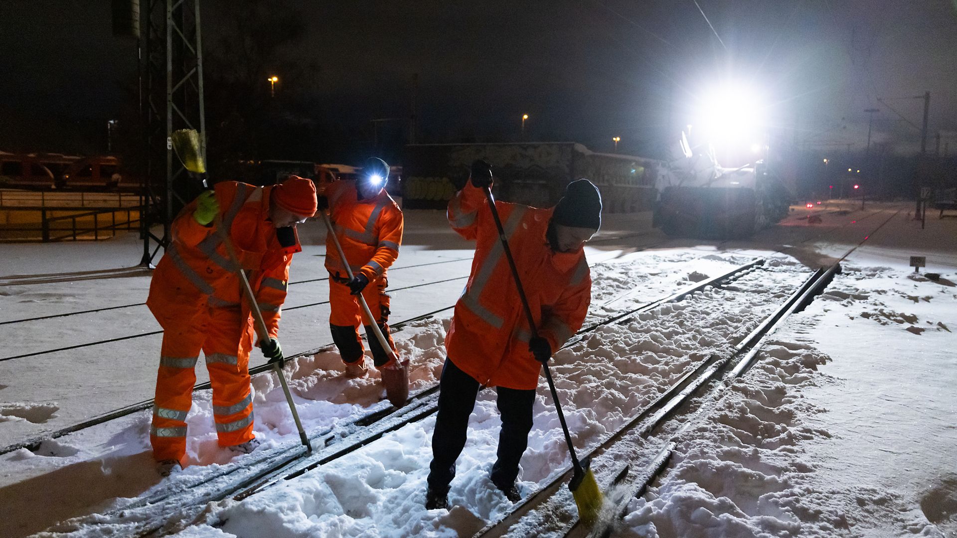 Mitarbeitende räumen verschneite Weichen in der Nähe von Braunschweig frei.