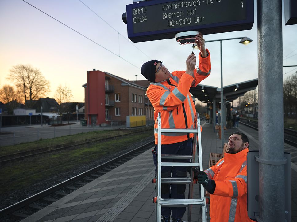 DB-Mitarbeiter reparieren Leuchten am Bahnsteig
