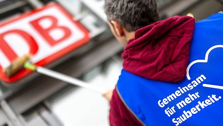 Mann putzt DB-Schild in Halle