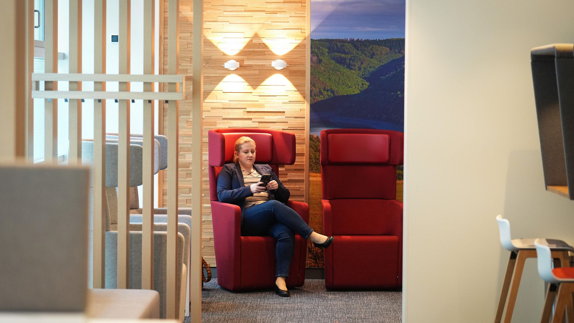 Frau sitzt auf einem roten Sessel im Wartebereich