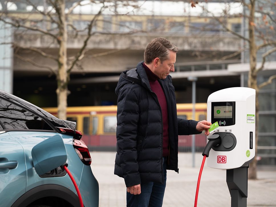 Ein Mann lädt sein privates E-Fahrzeug an einer Ladesäule der DB. 