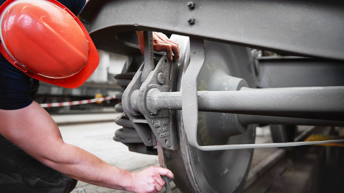 Ein Monteur arbeitet an der Bremse eines Zugwagons.